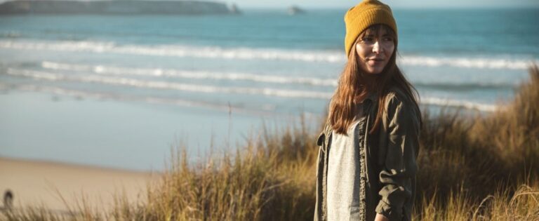 Frau mit Mütze am Meer dreht sich um Umschulung