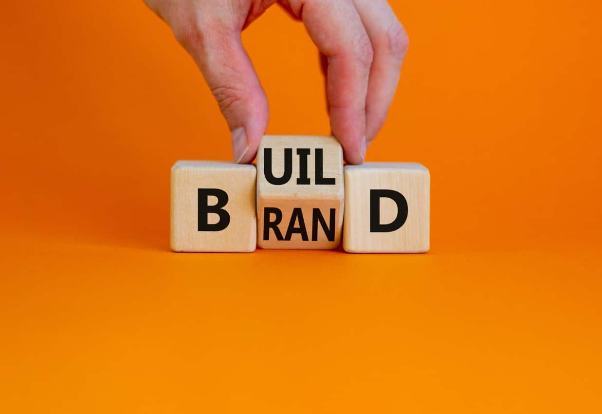 Digitale Avantgarde ; Würfel mit den Buchstaben Build Brand auf orangenem Hintergrund