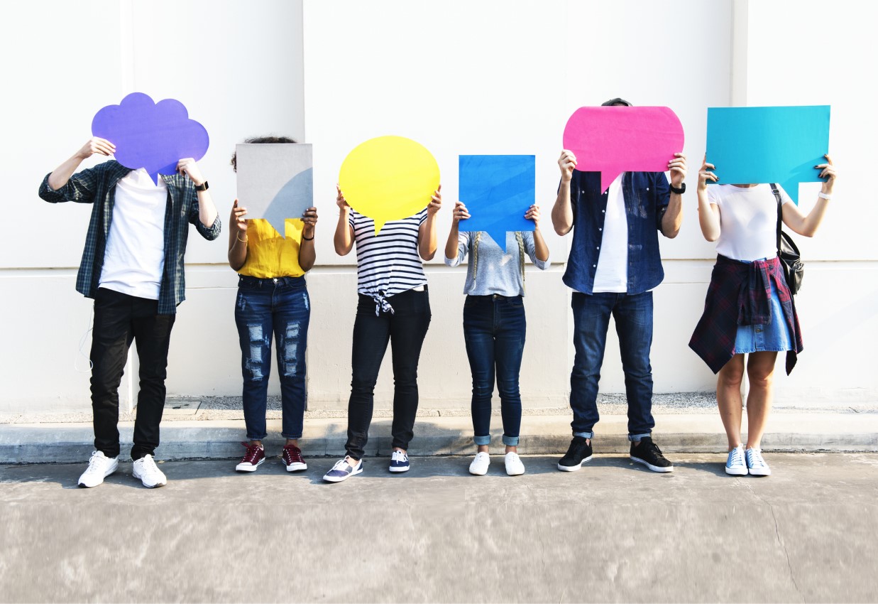 Social Media Kampagnen - sechs Personen stehen nebeneinander und halten bunte Sprechblasen in die Höhe