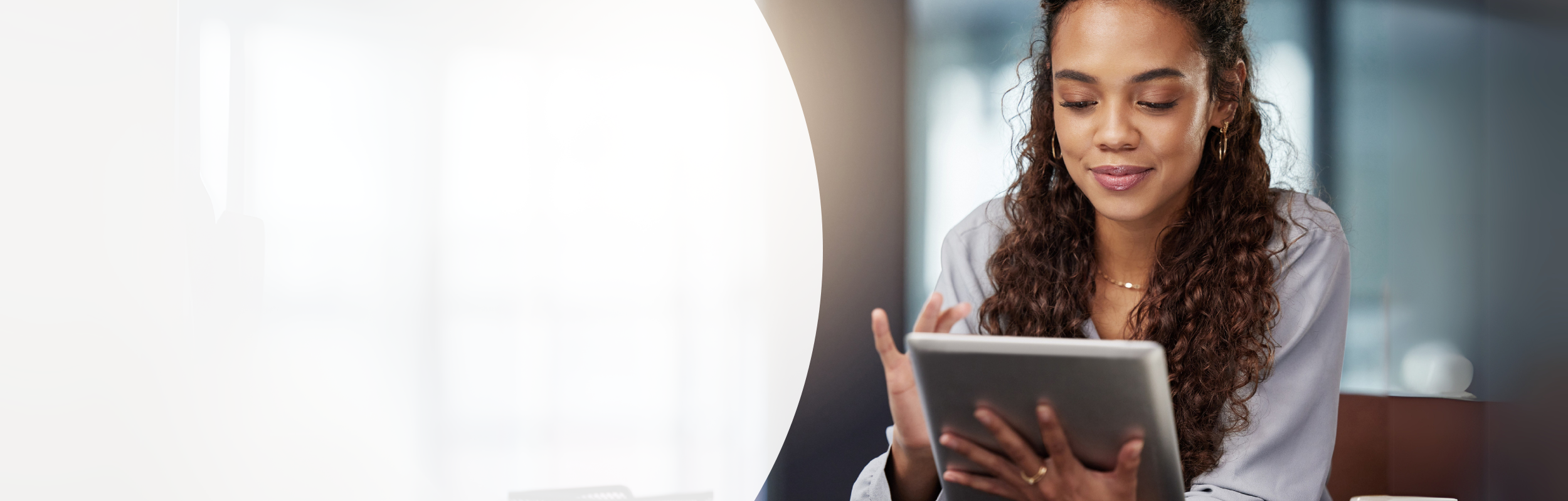 Frau mit langen brauen, lockigen Haaren mit Tablet in der Hand