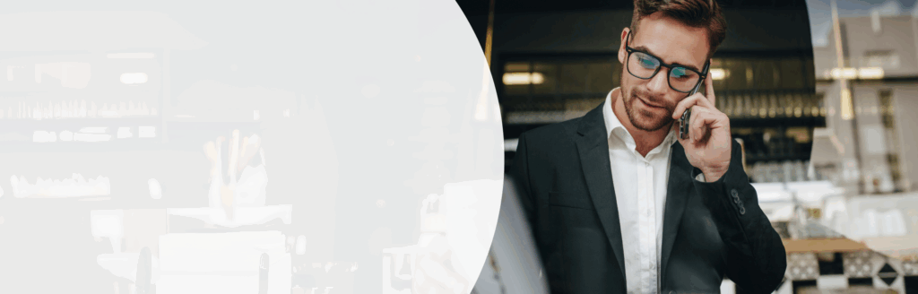 Mann mit weißem Hemd, Sakko und Brille telefoniert am Smartphone