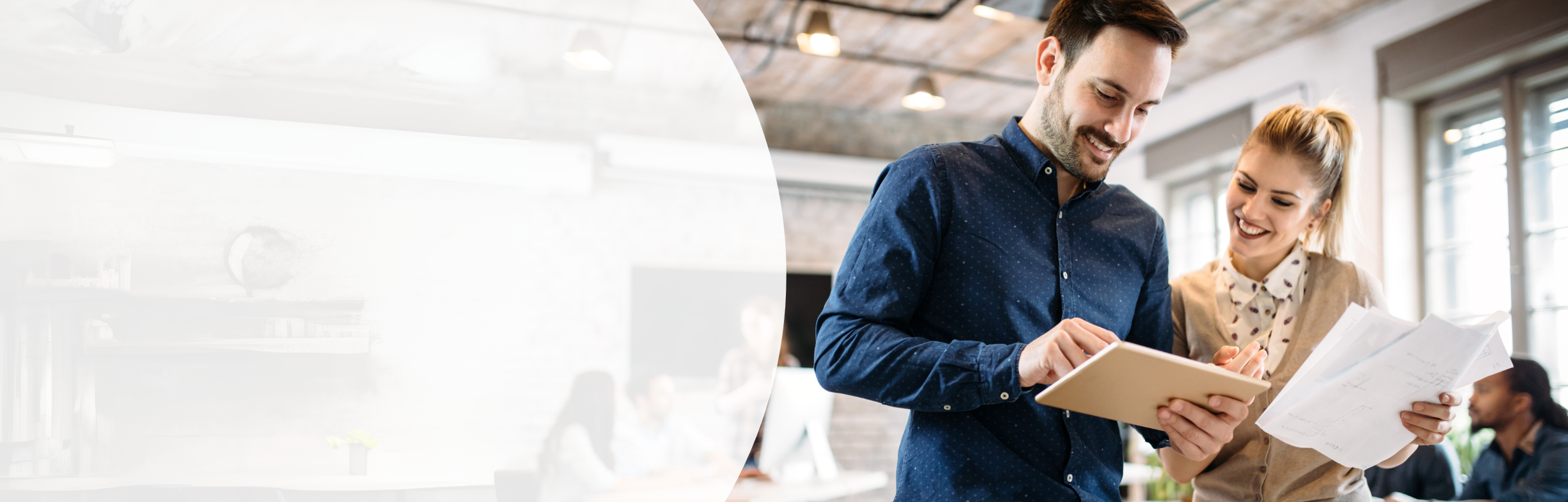 Eine Frau und ein Mann schauen in einem geschäftlichen Umfeld auf ein iPad, die Frau hält Zettel in der Hand