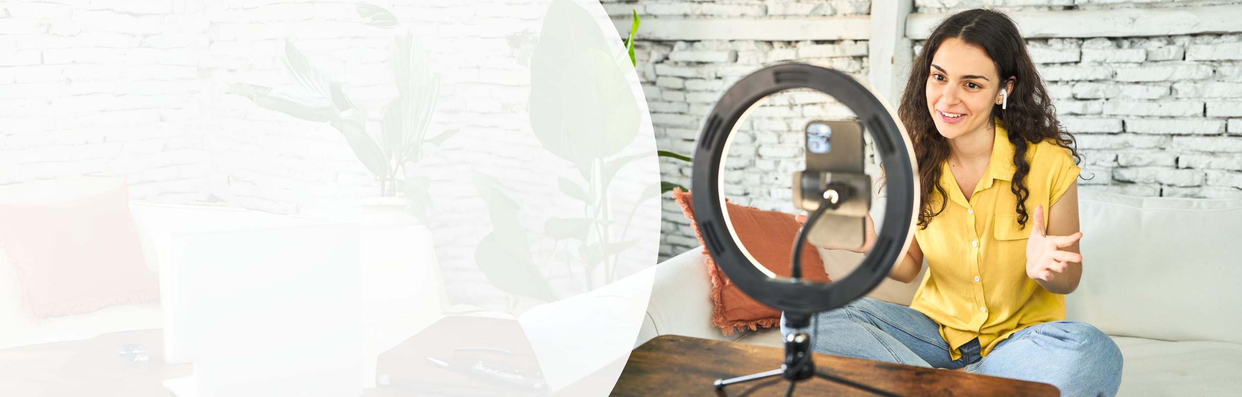 Frau mit gelber Bluse sitzt auf der Couch vor Ringlicht und nimmt Video am Smartphone auf