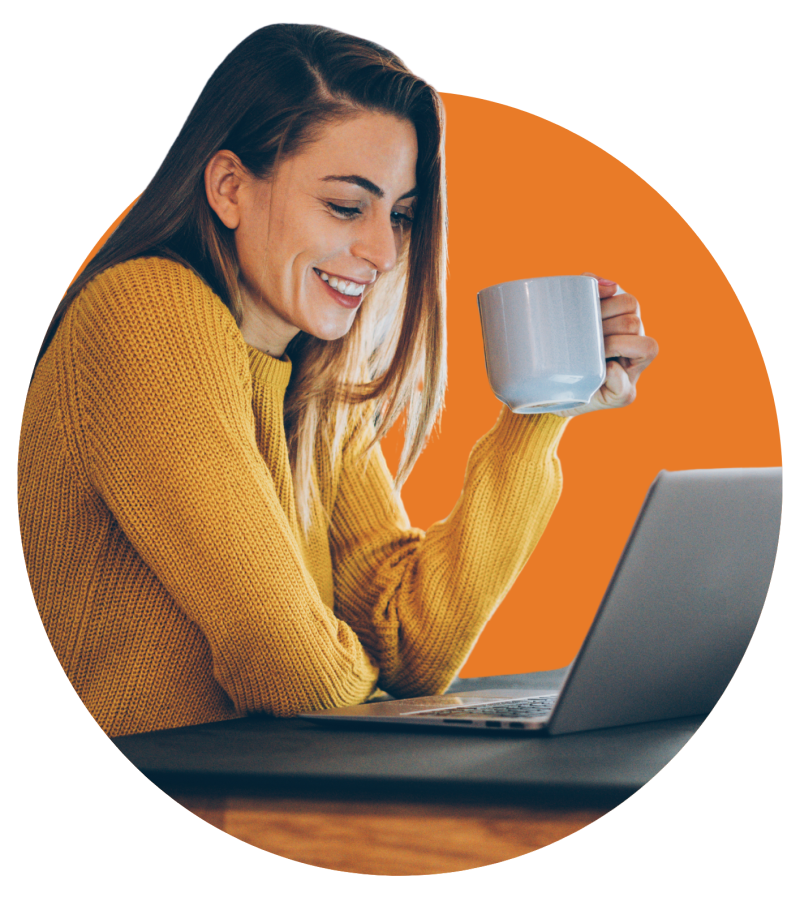 Frau mit gelbem Pulli und Kaffeetasse vor Laptop