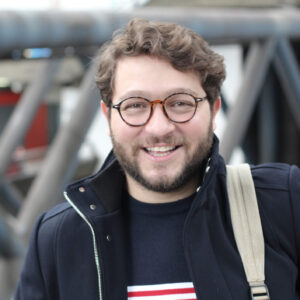 Portrait eines lächelnden jungen Mannes mit einer dunkelblauen Jacke.