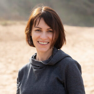 Portrait einer Frau mit schulterlangen brauen Haaren und eines schwarzen Pullovers.