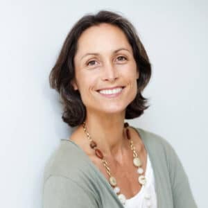 Portrait einer Dame mittleren Alters, die eine weiße Bluse und ein graue Weste trägt