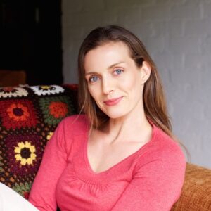 Portrait einer lächelnden Frau, die auf einer Couch sitzt.