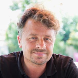 Portrait eines Mannes mittleren Alters mit lockigen braunen Haaren.