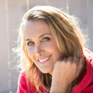 Portrait einer lächelnden blonden Frau in einem roten Pullover