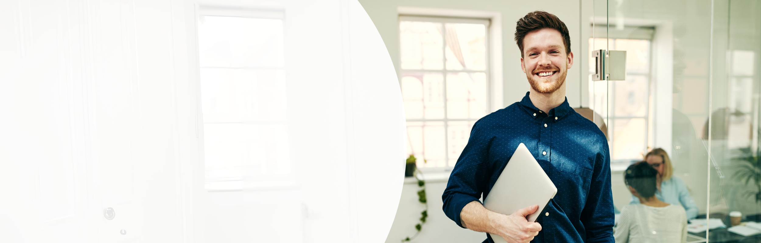 Mann in Geschäftsumfeld mit blauem Hemd und Laptop in der Hand