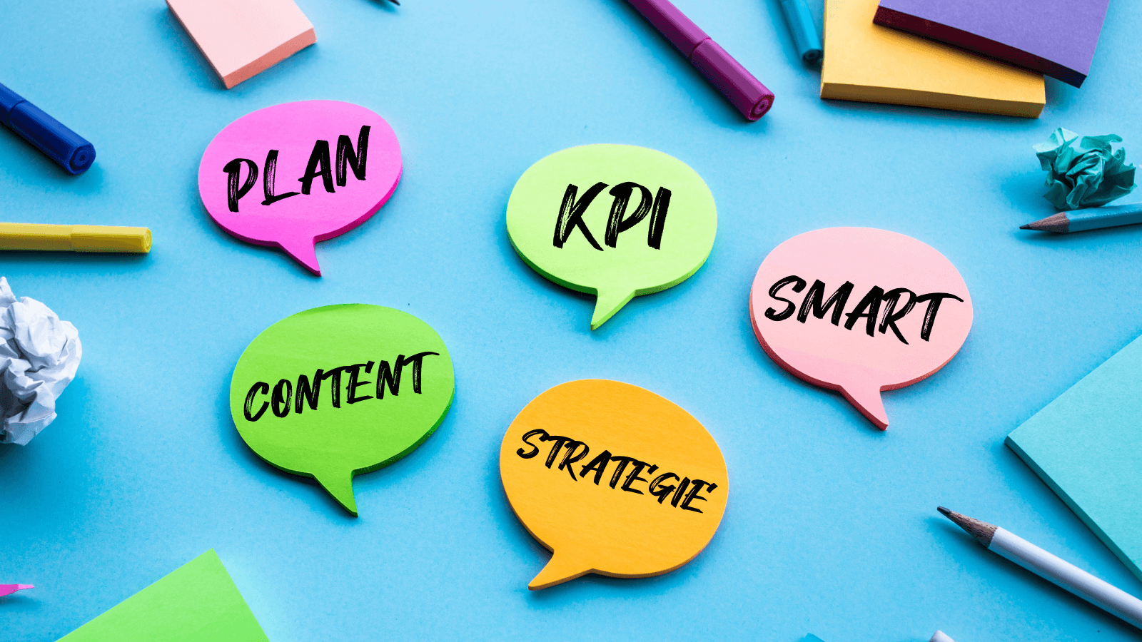 Bunte Post-Its in Sprechblasenform und Stifte liegen auf einem Tisch bereit, um einen Marketing Plan zu erstellen.